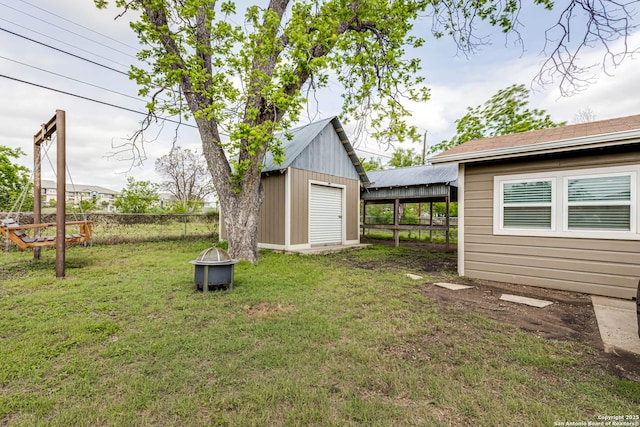 view of yard featuring a storage unit, fence, an outbuilding, and an outdoor fire pit