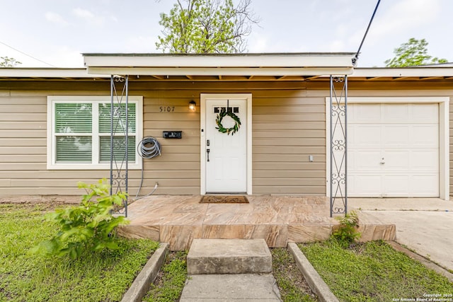 property entrance with an attached garage and concrete driveway