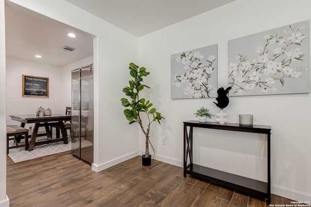 hallway featuring dark wood finished floors, baseboards, visible vents, and recessed lighting
