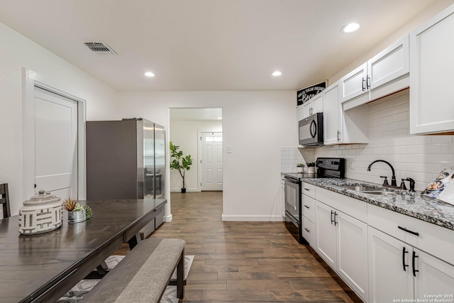 kitchen with a sink, stone counters, freestanding refrigerator, black microwave, and range with electric stovetop