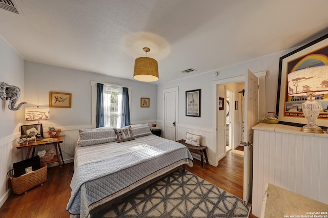 283 N Second St, Harper, TX 78631 - bedroom with wood finished floors, visible vents, and a wainscoted wall