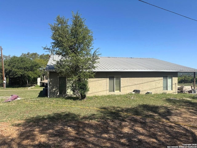 view of side of home featuring a lawn and metal roof