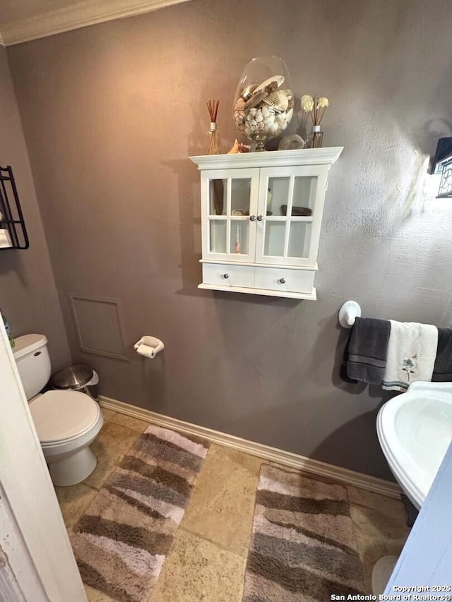 bathroom featuring crown molding, a sink, tile patterned flooring, and toilet