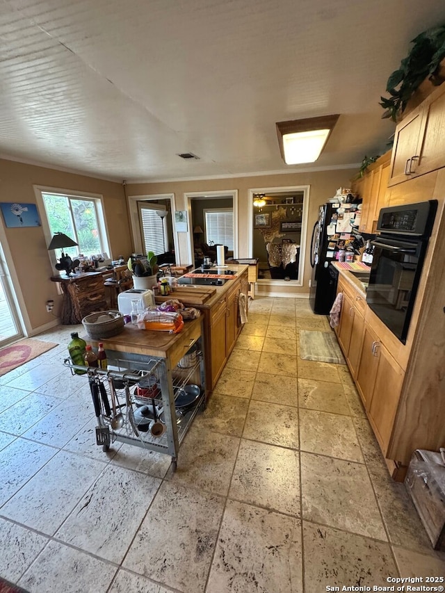 kitchen featuring a sink, baseboards, black appliances, and stone tile floors