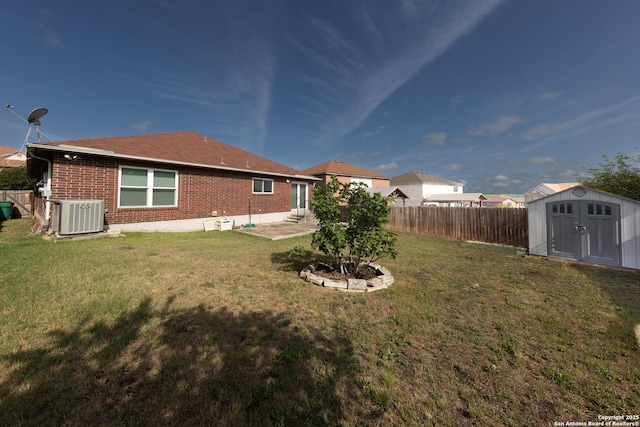 view of yard with a storage unit, an outbuilding, central AC, fence, and a patio area