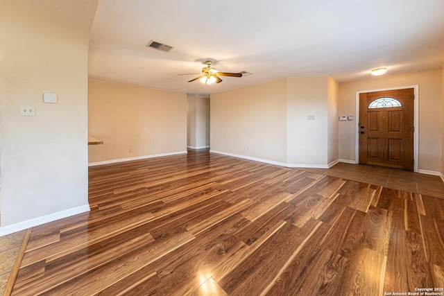 unfurnished living room with wood finished floors, visible vents, a ceiling fan, and baseboards