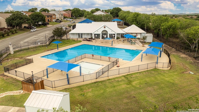 community pool featuring fence, a lawn, and a patio area