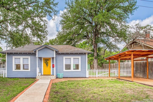 bungalow-style home featuring fence, a shingled roof, and a front lawn
