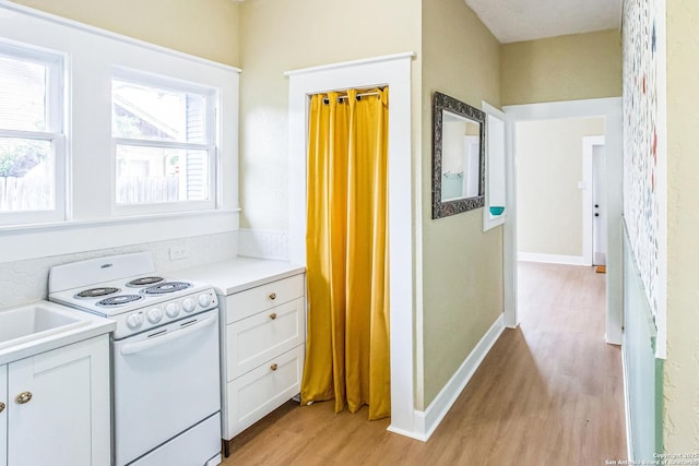 kitchen with white cabinetry, white electric stove, light countertops, and light wood-style floors