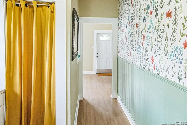 corridor with wood finished floors and a wainscoted wall