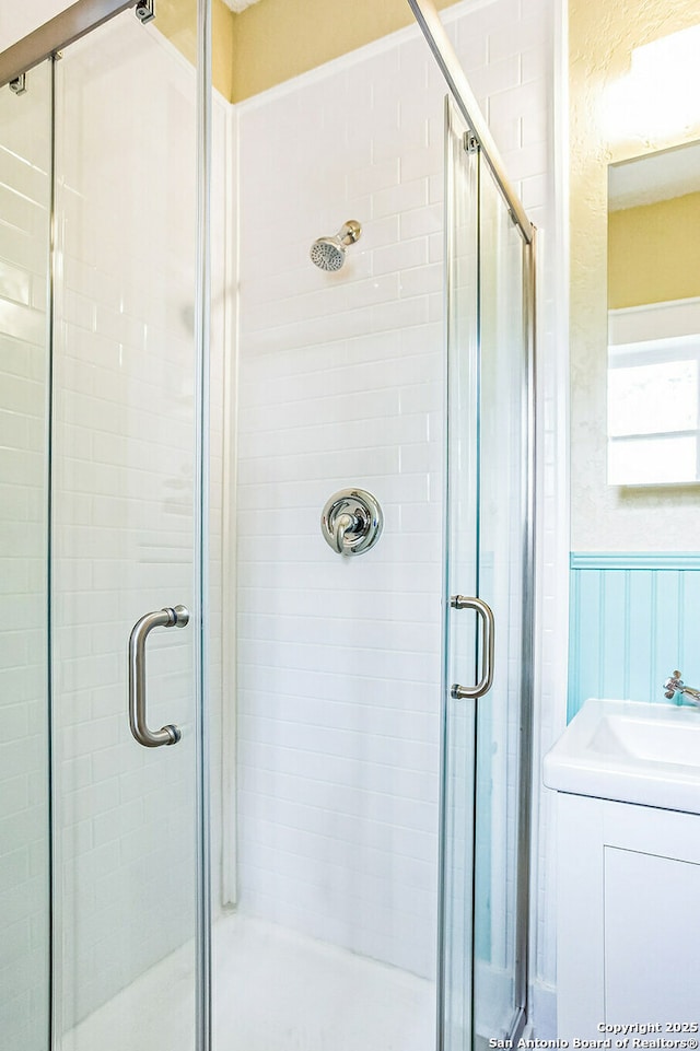 bathroom featuring a wainscoted wall and a stall shower