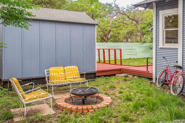 view of yard featuring a fenced backyard, a storage shed, an outdoor structure, an outdoor fire pit, and a deck