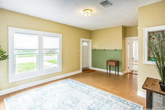 entrance foyer with baseboards, wood finished floors, and visible vents