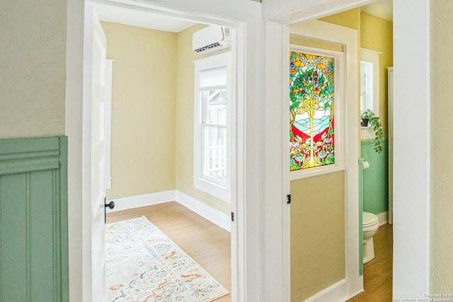 doorway to outside with a wall mounted AC, wood finished floors, and baseboards