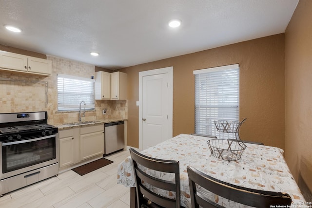 911 Porter St, San Antonio, TX 78210 - kitchen with white cabinets, stainless steel appliances, a sink, tasteful backsplash, and light stone counters