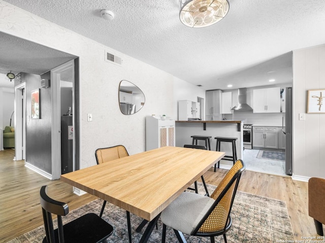 7906 Winsford, San Antonio, TX 78239 - dining space with light wood-style flooring, a textured ceiling, a textured wall, and visible vents