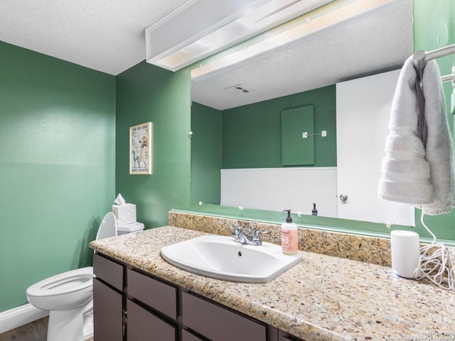 7906 Winsford, San Antonio, TX 78239 - bathroom with wood finished floors, toilet, vanity, baseboards, and a textured ceiling