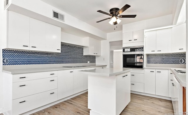 kitchen featuring stainless steel oven, ceiling fan, tasteful backsplash, and visible vents