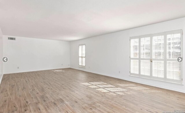 empty room featuring baseboards, wood finished floors, and visible vents