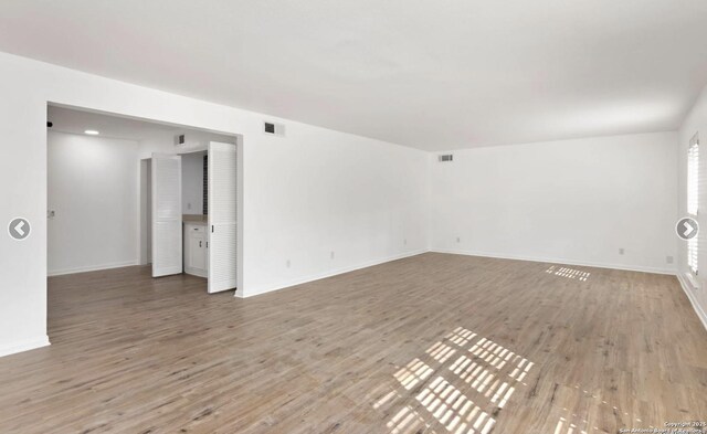 unfurnished room with baseboards, wood finished floors, and visible vents