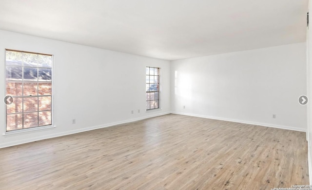 spare room with baseboards, light wood finished floors, and plenty of natural light