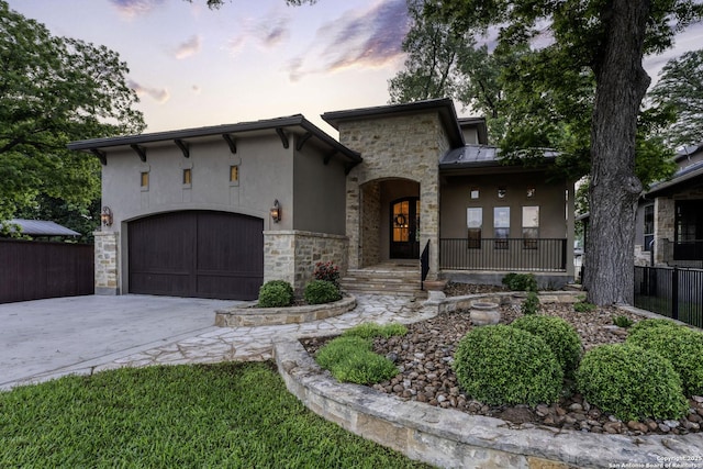 mediterranean / spanish house with stucco siding, stone siding, concrete driveway, and a garage