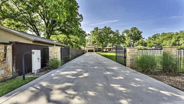 view of road featuring a gate, concrete driveway, and a gated entry