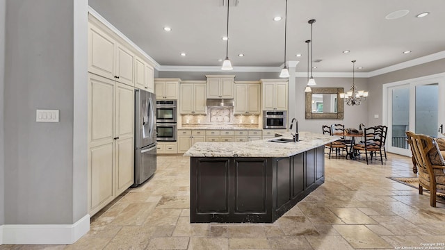 kitchen featuring stone tile flooring, cream cabinetry, appliances with stainless steel finishes, and a sink