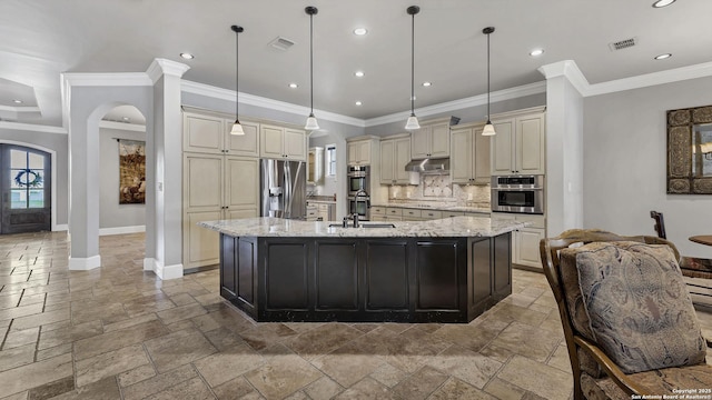 kitchen with stone tile floors, cream cabinets, appliances with stainless steel finishes, under cabinet range hood, and visible vents
