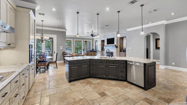 kitchen with a sink, arched walkways, stone tile floors, open floor plan, and appliances with stainless steel finishes
