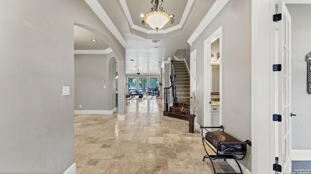 foyer featuring stone tile floors, arched walkways, french doors, a raised ceiling, and baseboards