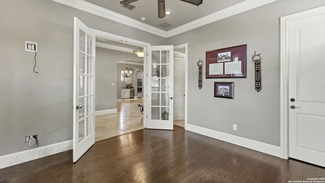 interior space with crown molding, ceiling fan with notable chandelier, french doors, baseboards, and visible vents