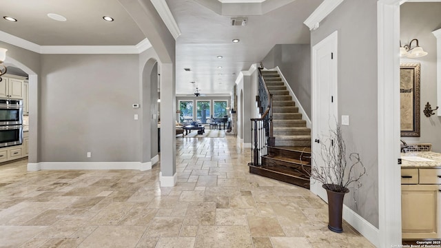 entrance foyer featuring stairway, visible vents, arched walkways, stone tile flooring, and baseboards