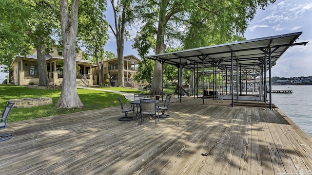 exterior space featuring a lawn, an outdoor fire pit, a boat dock, and a water view