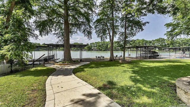 exterior space featuring fence, boat lift, a boat dock, and a water view