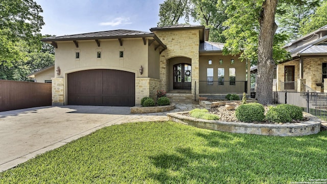 mediterranean / spanish-style home featuring a standing seam roof, driveway, stone siding, metal roof, and stucco siding