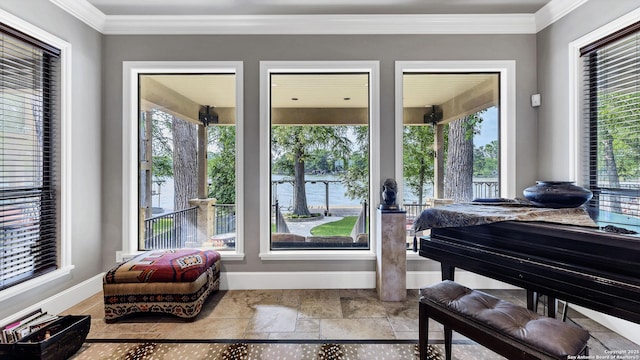 sitting room with baseboards, crown molding, and stone finish floor