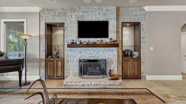 living area featuring stone tile flooring, arched walkways, baseboards, a fireplace, and ornamental molding