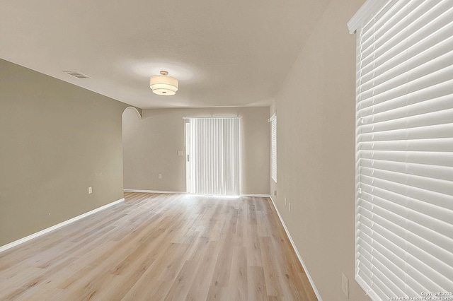 8906 Mission Brk, San Antonio, TX 78223 - unfurnished room featuring light wood finished floors, baseboards, visible vents, and arched walkways