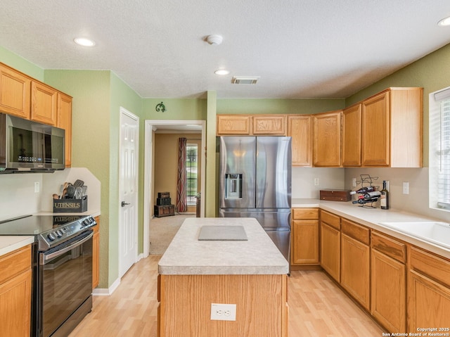 154 Elk Rdg, Canyon Lake, TX 78133 - kitchen with stainless steel appliances, light countertops, visible vents, light wood-type flooring, and a kitchen island
