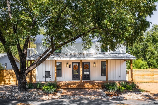 modern farmhouse featuring board and batten siding, fence, and covered porch