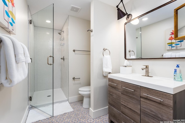 bathroom with toilet, baseboards, visible vents, a shower stall, and vanity