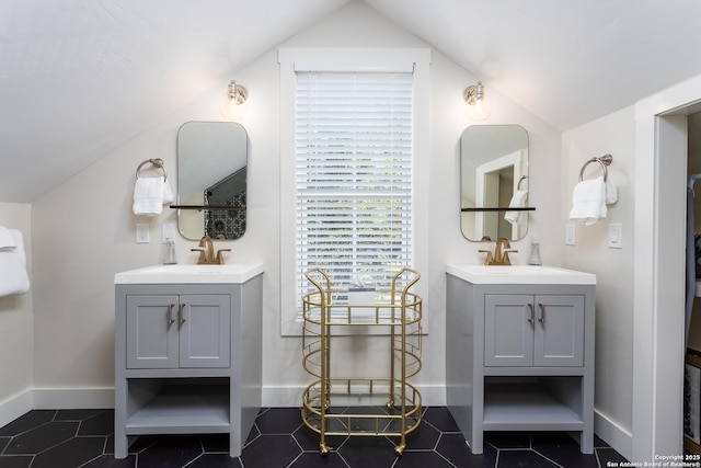 full bathroom featuring lofted ceiling, a sink, and two vanities
