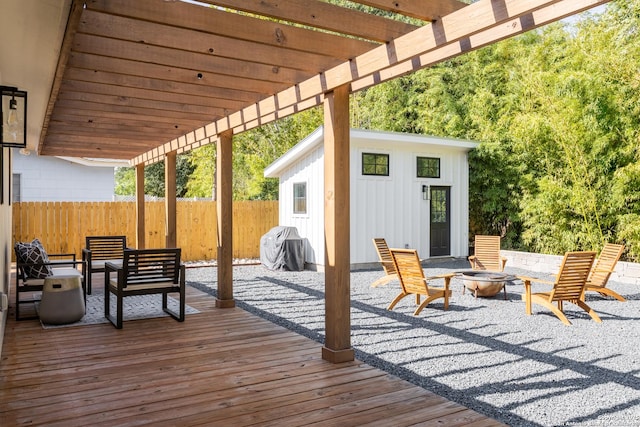 deck with area for grilling, fence, a pergola, an outbuilding, and a fire pit