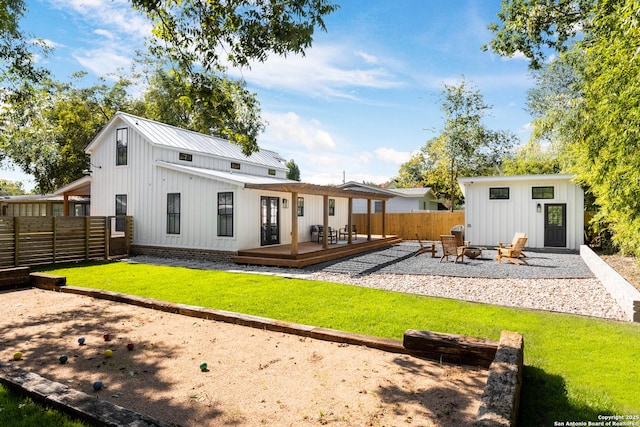 rear view of house featuring a fire pit, fence, a wooden deck, board and batten siding, and a yard