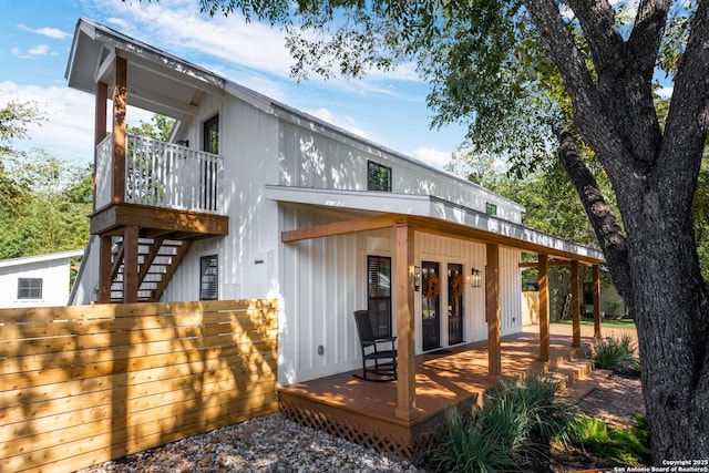 rear view of property with fence, a wooden deck, and french doors