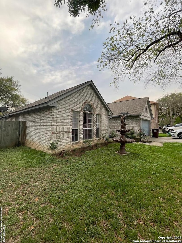 view of home's exterior with fence, brick siding, a yard, and a garage