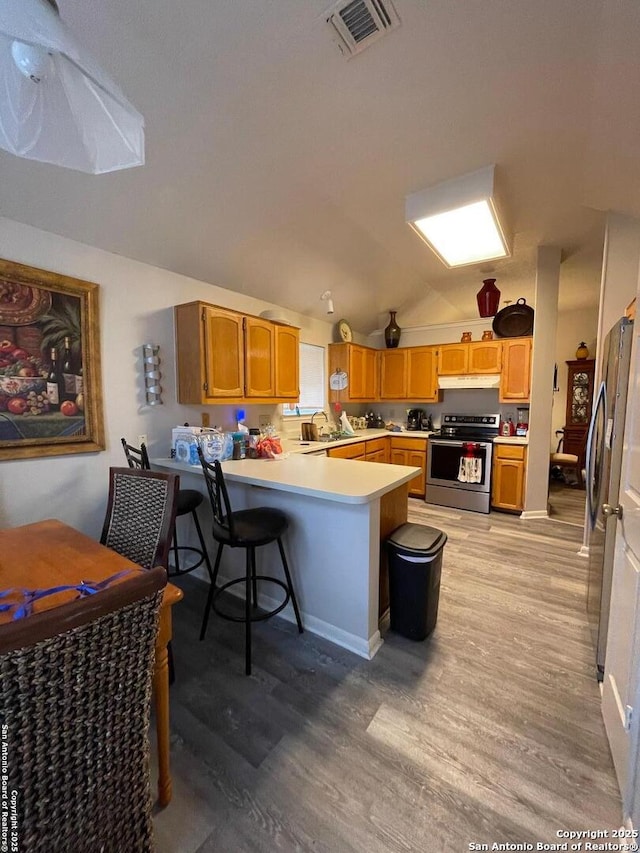 kitchen featuring stainless steel appliances, light countertops, visible vents, a peninsula, and light wood-style flooring
