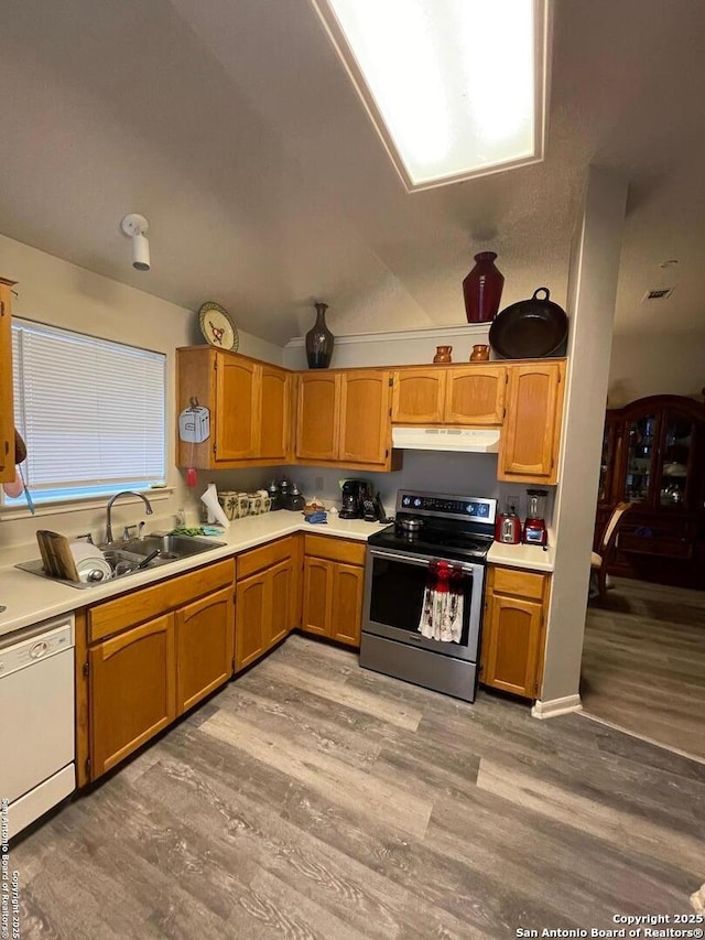 kitchen featuring white dishwasher, a sink, stainless steel electric range oven, light wood-style floors, and under cabinet range hood