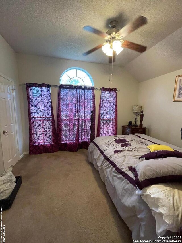 carpeted bedroom featuring ceiling fan, lofted ceiling, and a textured ceiling